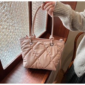 Vue détaillée du sac seau matelassé rose avec cuir souple et poignée nouée élégante