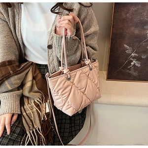 Détail du sac à bandoulière rose matelassé avec chaîne porté avec une tenue d'automne