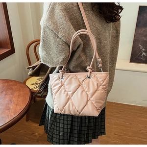 Détail du sac seau rose matelassé montrant les coutures fines et la boucle en métal argenté