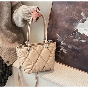 Détail du sac bandoulière beige matelassé avec losanges et œillets en métal argenté