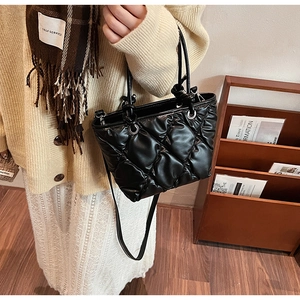Détail du sac seau noir matelassé avec œillets métalliques et texture souple