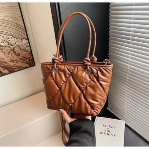 Détail du sac seau marron matelassé avec une poignée décorative nouée et cuir souple