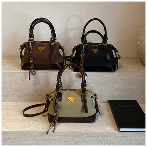 Drei schicke Nylon-Handtaschen mit Lederbesatz, Goldlogo und Quasten auf Steinstufen