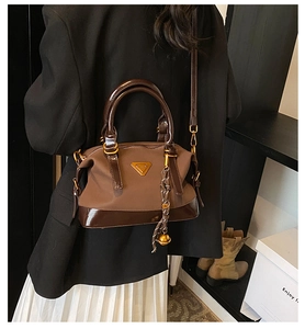 Detail einer braunen Vintage-Handtasche aus mattem Canvas mit glänzenden Lederakzenten