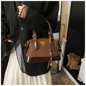 Detailansicht der dunkelbraunen Handtasche mit mattem Finish und goldenem Logo-Schild
