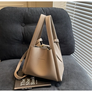 Detail of minimalist pebble leather bucket bag with brand logo and soft handles