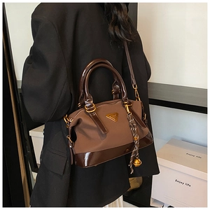 Detail einer braunen Webhandtasche mit glänzendem Lederbesatz und goldenen Beschlägen