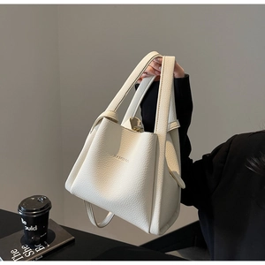 Detail of off-white lychee grain leather handbag with embossed logo and coffee cup props