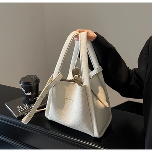 Close-up of beige lychee texture leather tote bag with embossed logo on a black table