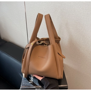 Close-up of caramel bucket bag featuring lychee texture and golden hardware details