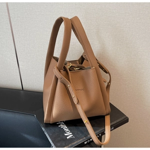 Detail of brown litchi pattern leather bucket bag with embossed logo and metal buckle