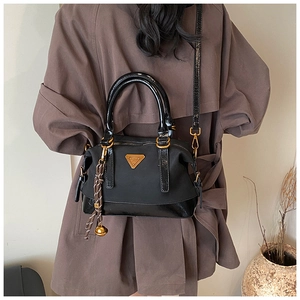 Schicke schwarze Nylon-Kissentasche kombiniert mit einem braunen Trenchcoat