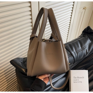 Detail of taupe lychee leather bucket bag with embossed logo and gold metal hardware
