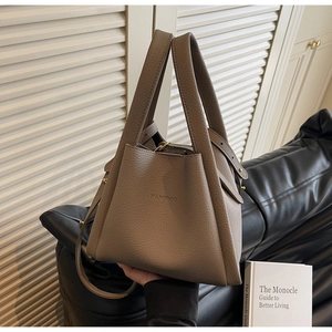 Detailed close-up of taupe pebbled leather bucket bag featuring elegant gold hardware
