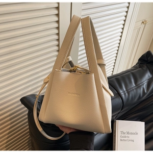 Detail of cream beige lychee pattern leather bucket bag with top handles and logo