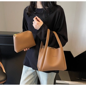 Detail of brown leather tote and pouch set featuring pebbled texture and BAMBOO logo