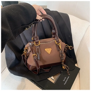 Detailansicht der braunen Boston-Tasche mit Metall-Logo und Reißverschluss-Akzenten