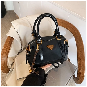 Detail einer schwarzen Boston-Tasche aus Nylon mit Goldbeschlägen und Quastenanhänger