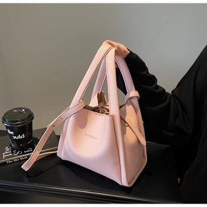 Detail of pink lychee grain leather bucket bag with top handles and gold buckle strap