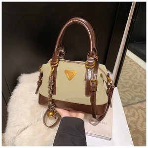 Detail einer Boston-Tasche aus Leder in Olivgrün und Braun mit goldenem Metalldreieck