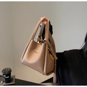 Close-up of lychee grain leather bucket bag featuring embossed logo and shoulder strap