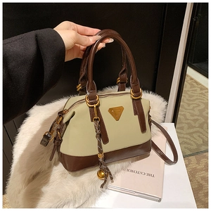 Detail einer eleganten zweifarbigen braunen Tasche mit Metallplakette und Anhänger