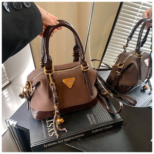 Detailansicht der braunen Boston Bag mit goldener Hardware und Logo-Plakette