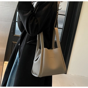 Chic elephant grey lychee pattern leather bucket bag held by a model in casual attire