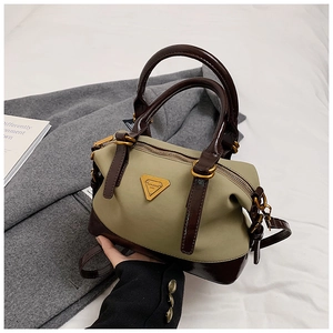 Detail der olivgrünen Bowling-Tasche mit dunkelbraunen Ledergriffen und Goldbeschlägen