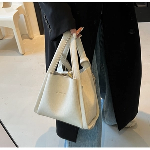 Close-up of the debossed BAMIROO logo on a cream lychee pattern leather bucket bag