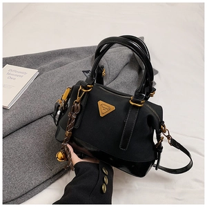 Details einer schwarzen Stoffhandtasche mit goldenem Dreieckslogo und Metallglocke