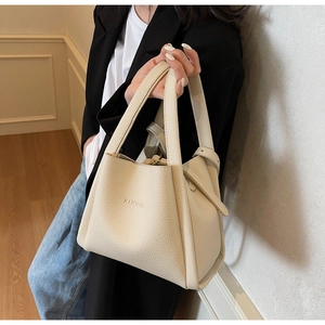 Detail of lychee pattern leather handbag with embossed letters and adjustable strap