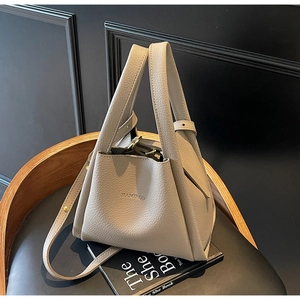 Detail of beige litchi grain leather bucket bag with top handle and adjustable strap