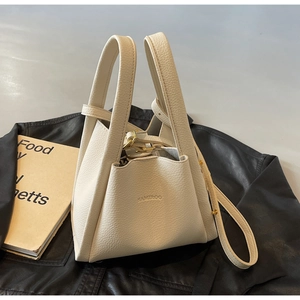 Detailed macro of cream lychee texture leather bucket bag with golden hardware accents