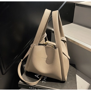 Detail of beige lychee grain leather bucket bag with top handles and adjustable strap