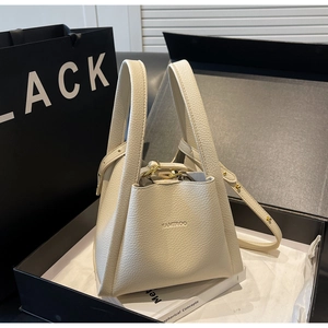 Macro view of cream lychee texture leather bucket bag with gold hardware and branding