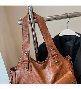 Detail der braunen Vintage PU-Tragetasche mit breitem Gurt und Metallnieten