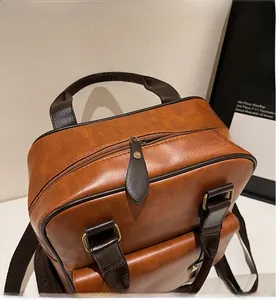 Close-up of smooth metal zipper and textured brown PU leather handle on a vintage backpack