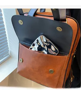 Close-up of durable front pocket with magnetic snap on vintage faux leather backpack
