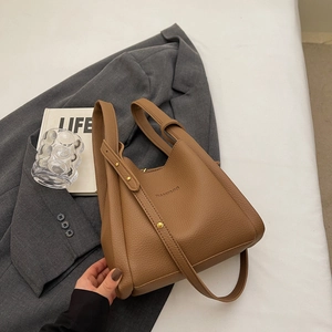 Brown litchi grain leather bucket bag with top handles and gold-studded shoulder strap