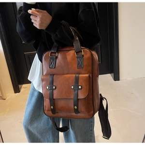 Detail of vintage brown leather backpack with buckled front pocket and sturdy top handle