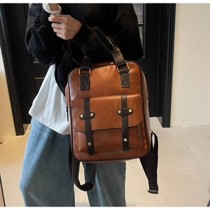 Close-up of brown PU leather backpack featuring golden studs and front flap pocket detail