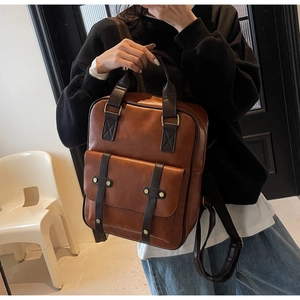 Detail of retro dual-tone backpack in caramel brown with rivet pocket and top handle