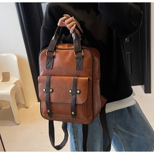 Detail of vintage brown PU leather backpack with buckle strap and gold stud accents