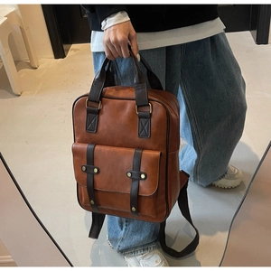 Detail of vintage brown PU leather backpack featuring golden studs and magnetic flap pocket
