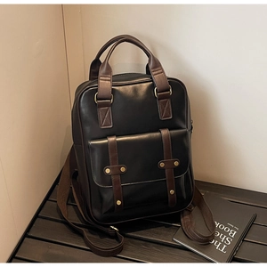 Close-up of retro black faux leather backpack with brown straps on a wooden bench