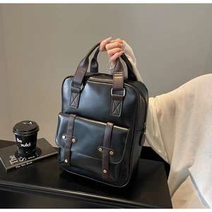 Close-up of retro black faux leather backpack with brown trim and vintage metal hardware