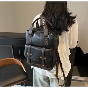 Detailed back view of vintage black PU leather backpack with brown straps on model