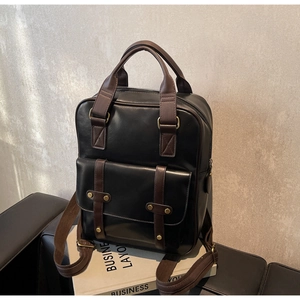 Detail of vintage black PU leather backpack with brown handles and gold metal hardware
