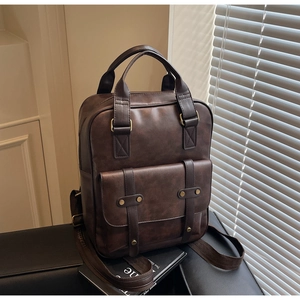 Detail of dark brown vintage backpack with leather texture and golden rivets on black bench